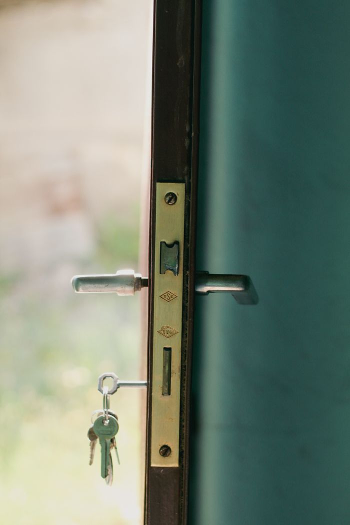 A close-up view of a door lock with inserted keys, illuminated by natural sunlight.