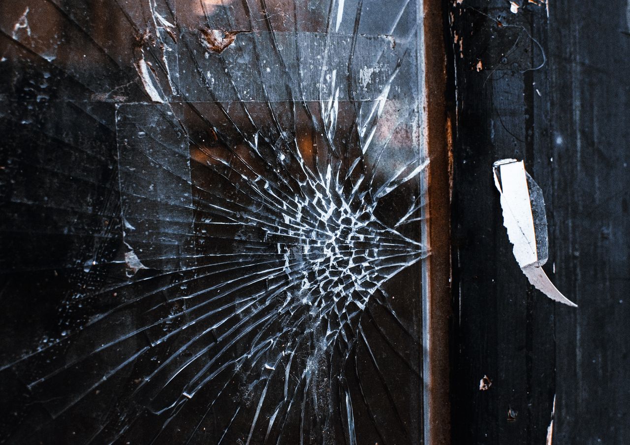 Close-up of a cracked window with a weathered wooden frame and grunge texture.
