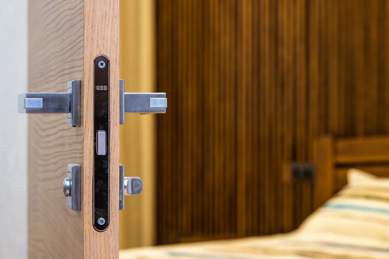 Crafting Captivating Headlines: Your awesome post title goes here Opened doorway with lock and simple metal handle in light room with wooden bed